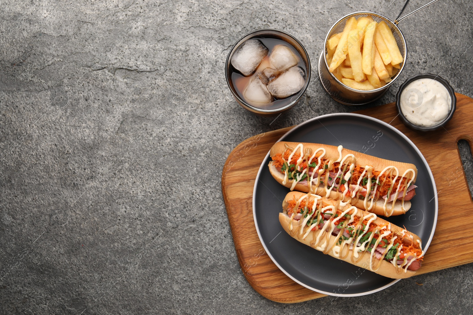 Photo of Delicious hot dogs with bacon, carrot and parsley served on grey table, flat lay. Space for text