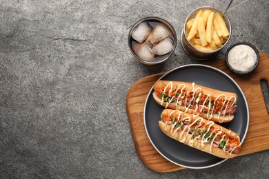 Delicious hot dogs with bacon, carrot and parsley served on grey table, flat lay. Space for text