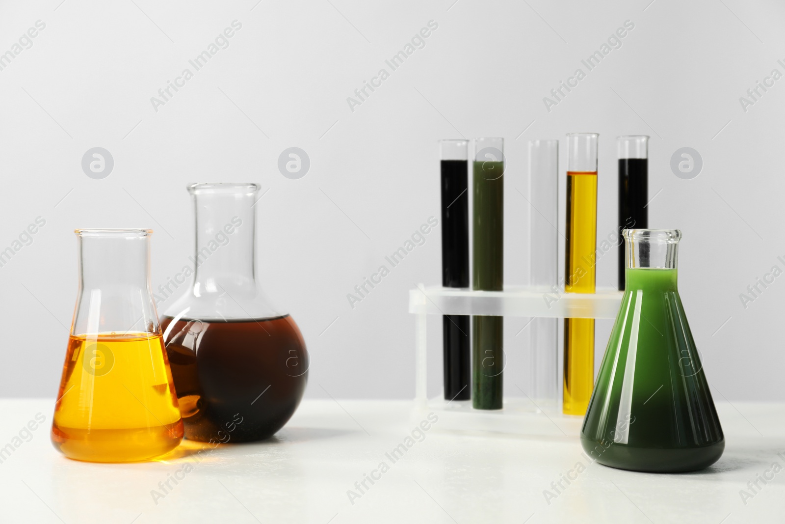 Photo of Laboratory glassware with different types of oil on white table