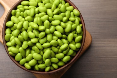 Photo of Bowl of delicious edamame beans on wooden table, top view