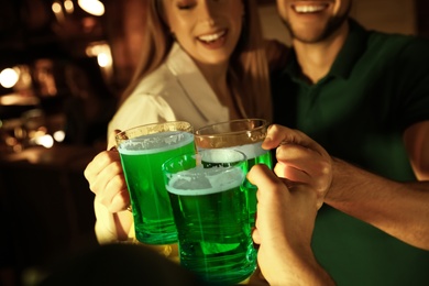Photo of People with beer celebrating St Patrick's day in pub, focus on hands