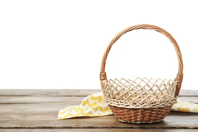 Empty wicker basket and cloth on wooden table against white background, space for text. Easter holiday