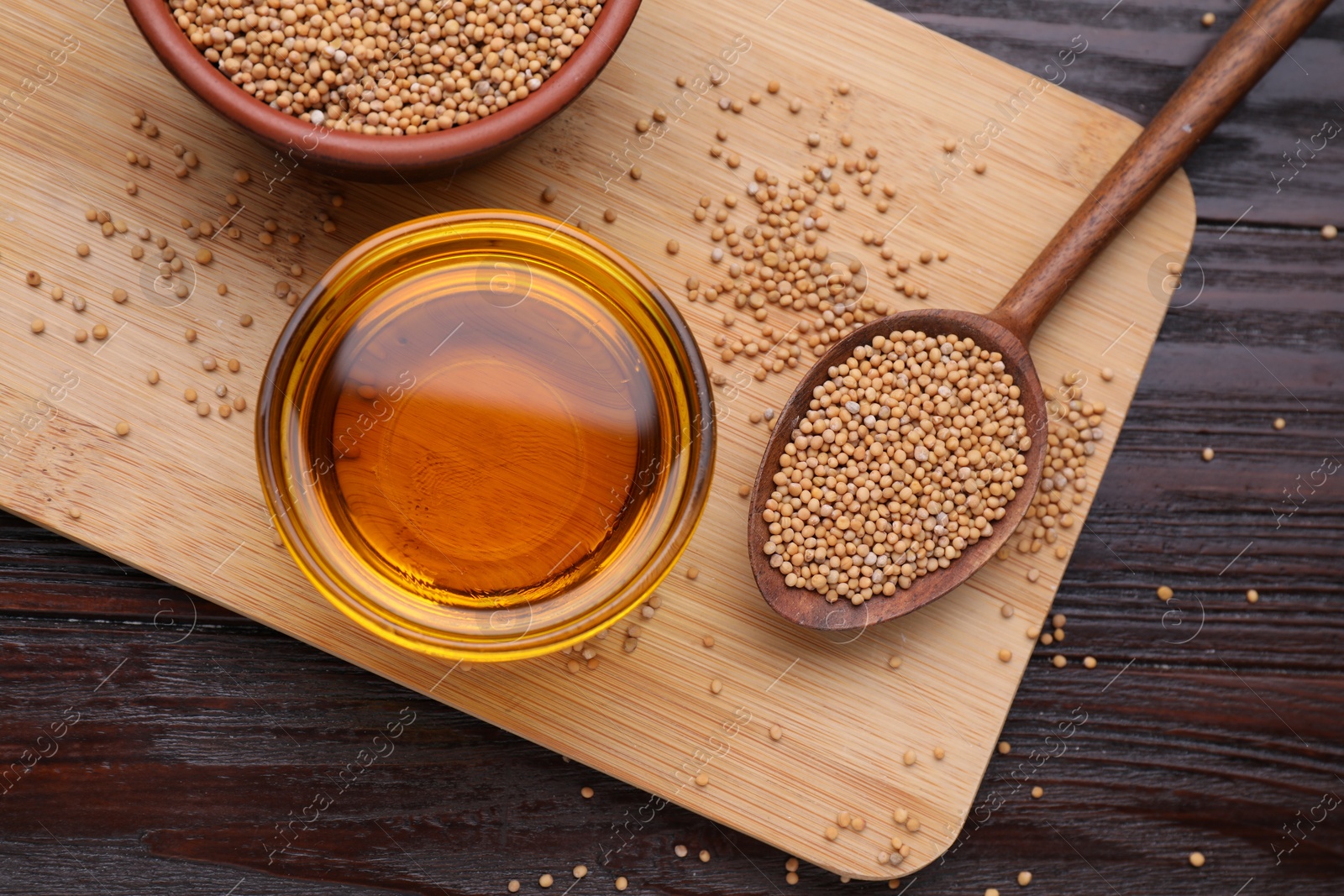 Bowl of natural oil and mustard seeds on wooden table, flat lay Photo of Bowl of natural oil and mustard seeds on wooden table, flat lay