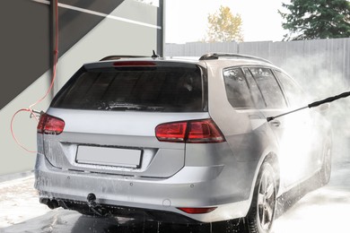 Man washing auto with high pressure water jet at outdoor car wash, closeup