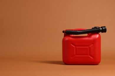 New red plastic canister on brown background. Space for text
