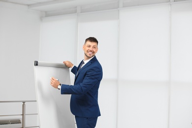 Professional business trainer near flip chart board indoors. Space for text