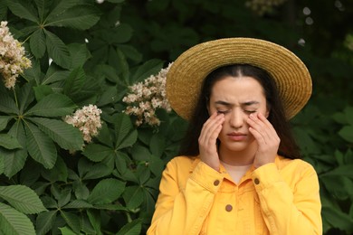 Woman suffering from seasonal spring allergy near tree in park