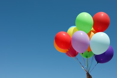 Photo of Woman with bunch of colorful balloons against blue sky. Space for text