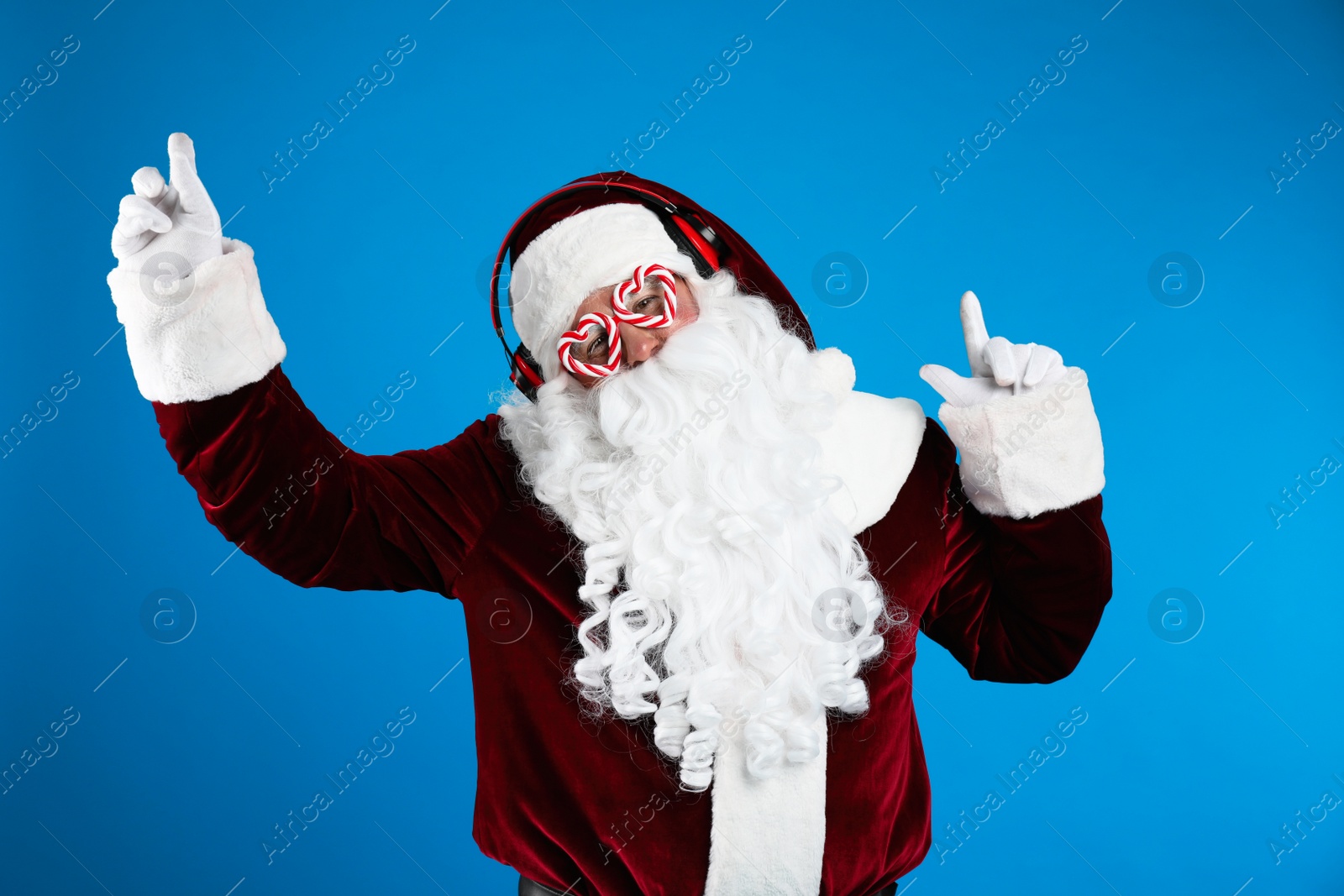 Photo of Santa Claus with headphones listening to Christmas music on blue background