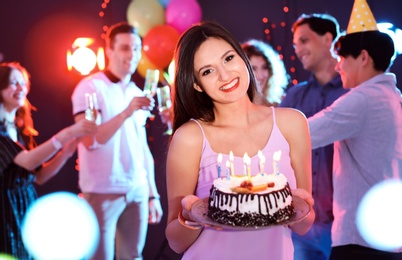 Photo of Young woman with birthday cake at party in nightclub