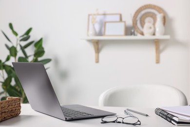 Photo of Home office. Laptop, glasses and stationery on white desk indoors. Space for text