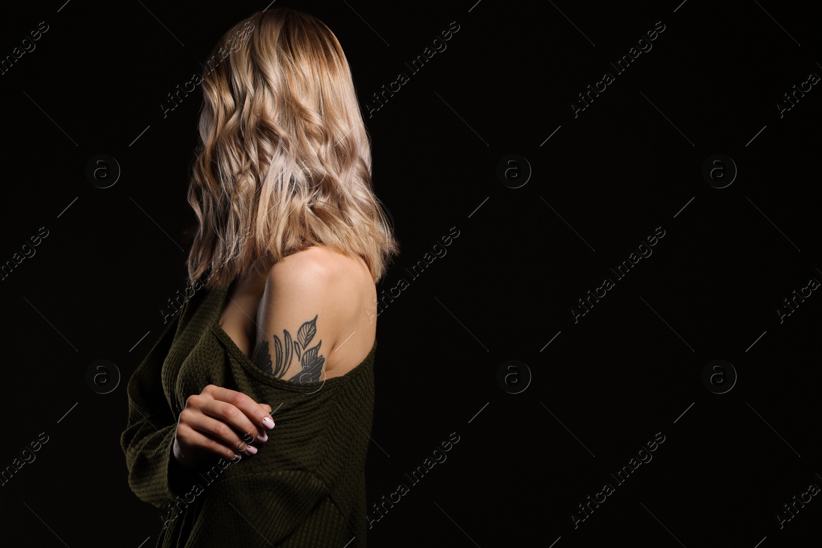 Photo of Beautiful woman with tattoos on arm against black background. Space for text