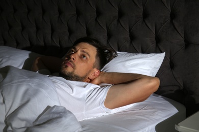 Man suffering from insomnia in bed at home