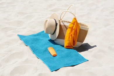 Photo of Blue towel, bag and accessories on sandy beach