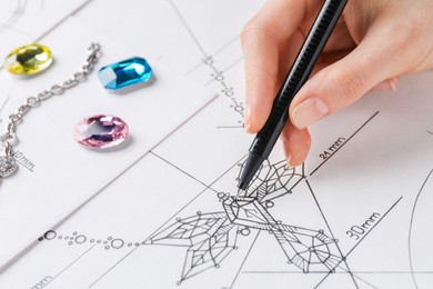 Photo of Jeweler drawing sketch of elegant necklace on paper, closeup