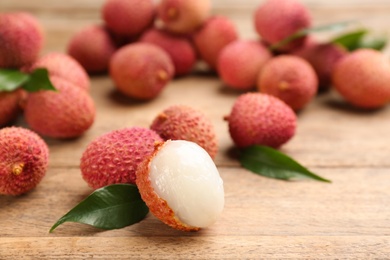 Fresh ripe lychees with leaves on wooden table, closeup