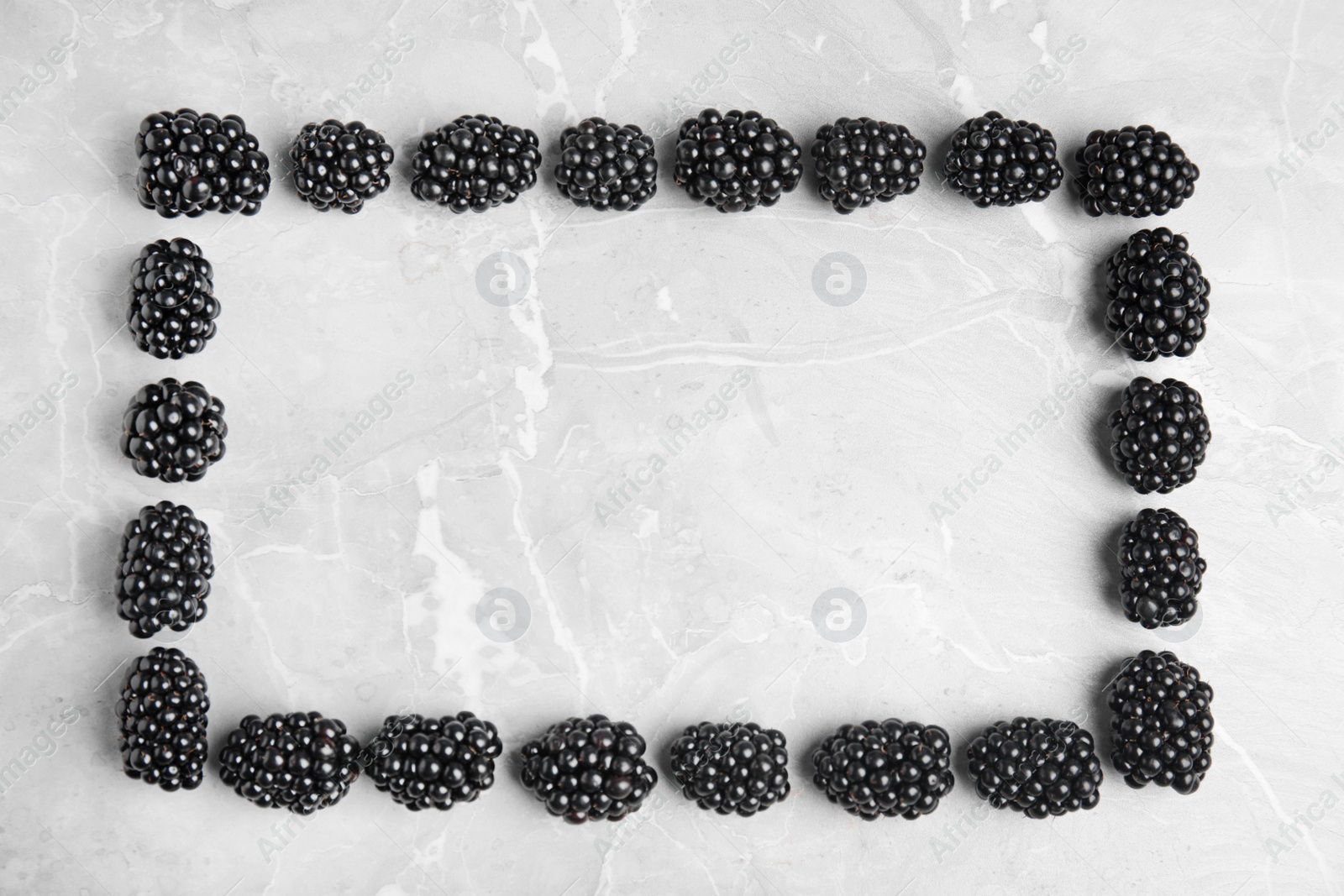 Photo of Frame made of tasty blackberries on grey marble table, top view with space for text