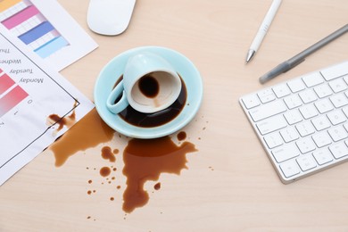 Photo of Cup with saucer and coffee spill on wooden office desk, above view