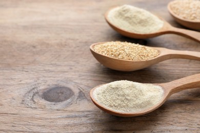 Spoons with quinoa flour and seeds on wooden table, closeup. Space for text