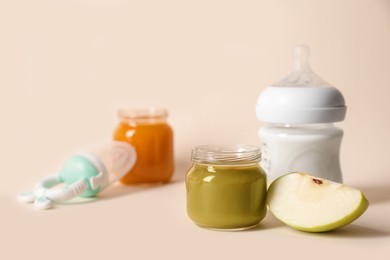 Photo of Jar with healthy baby food, bottle of milk and apple on beige background. Space for text