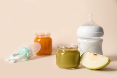 Jar with healthy baby food, bottle of milk and apple on beige background. Space for text