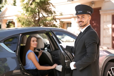 Handsome driver opening car door for young businesswoman. Chauffeur service