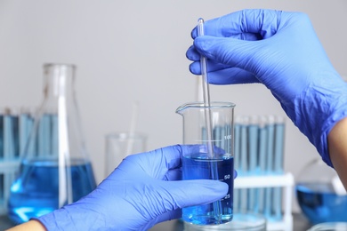 Photo of Doctor stirring liquid with glass rod, closeup. Laboratory analysis