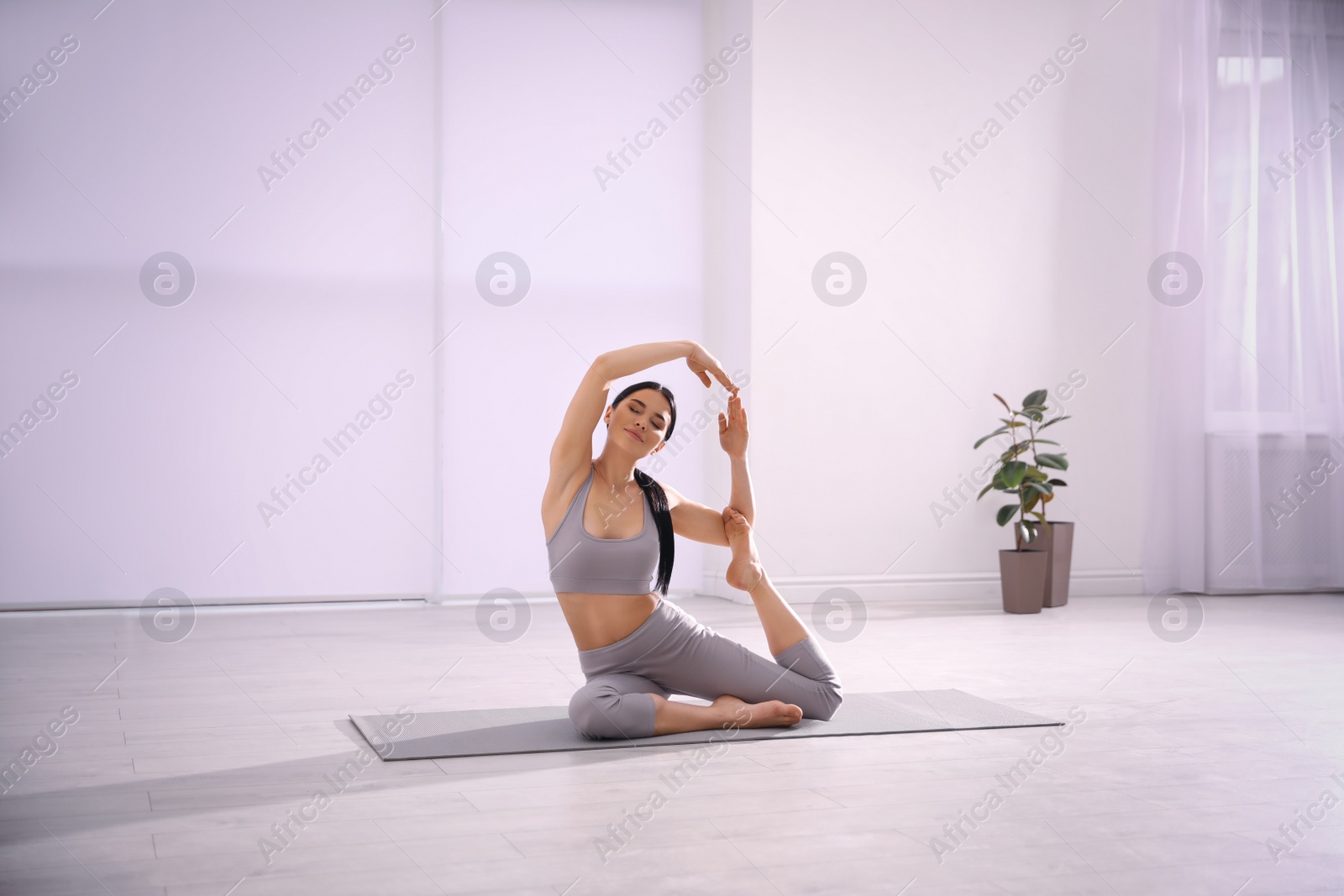 Photo of Young woman practicing mermaid asana in yoga studio. Eka Pada Rajakapotasana pose