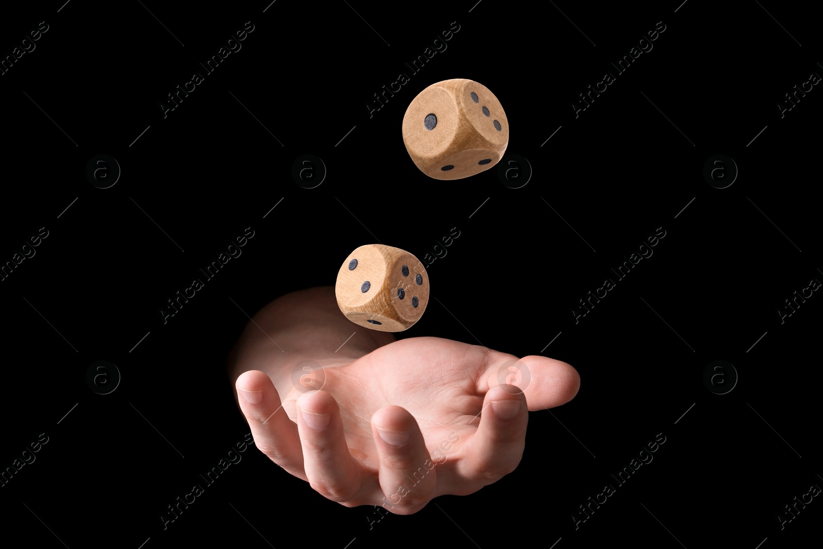 Image of Man throwing wooden dice on black background, closeup