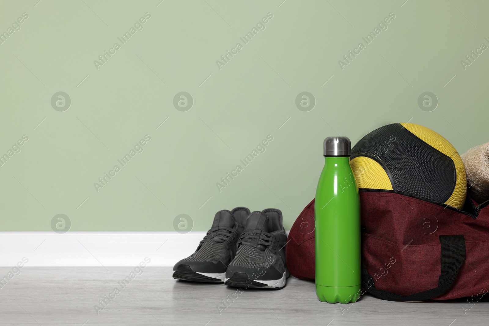 Photo of Gym bag and sports equipment on floor indoors, space for text