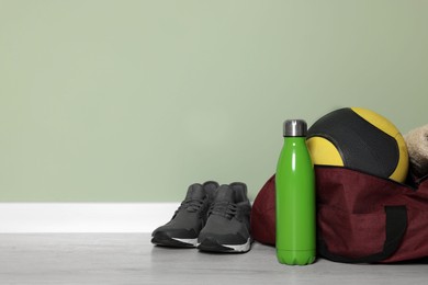 Photo of Gym bag and sports equipment on floor indoors, space for text