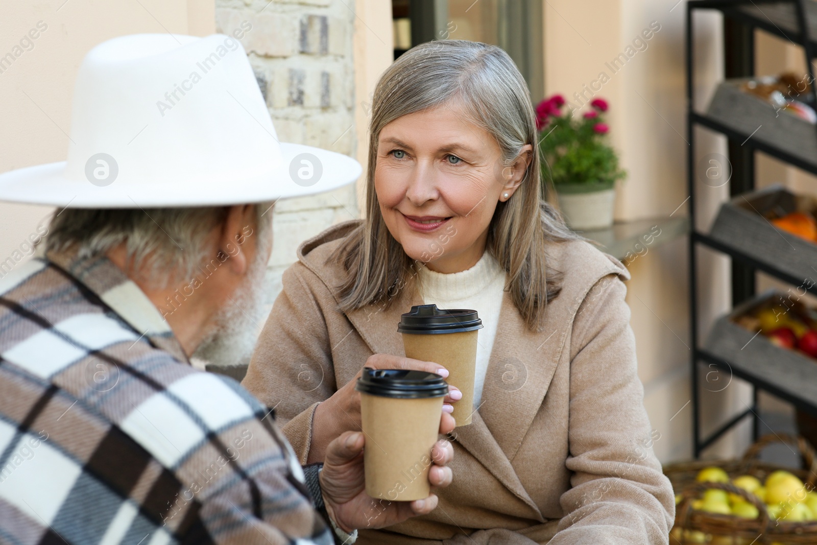 Photo of Affectionate senior couple sitting in outdoor cafe and drinking coffee, space for text