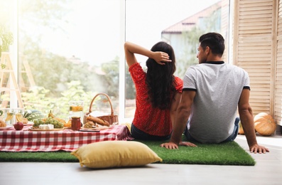 Photo of Couple imitating picnic at home, back view