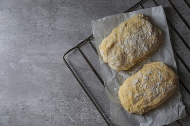 Raw dough and flour on grey table, top view with space for text. Cooking ciabatta