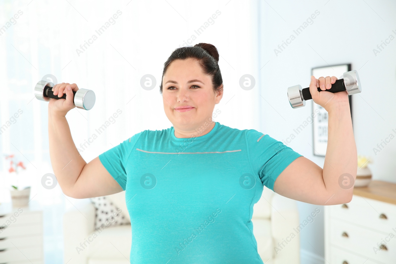 Photo of Overweight woman doing exercise with dumbbells at home