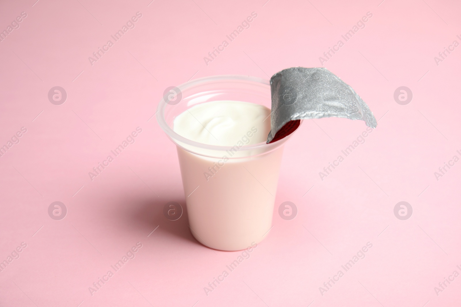 Photo of Plastic cup with creamy yogurt on color background