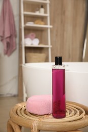 Photo of Bottle of shower gel and sponge on wicker table near tub in bathroom, space for text