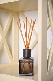 Photo of Aromatic reed freshener on wooden shelf indoors