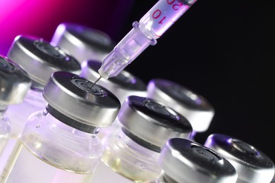 Photo of Filling syringe with medicine from vial on color background, closeup