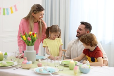 Happy family celebrating Easter at served table in room