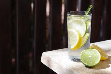 Photo of Summer refreshing lemonade and ingredients on light table outdoors, space for text