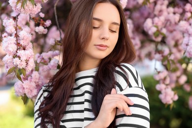 Beautiful woman near blossoming tree on spring day