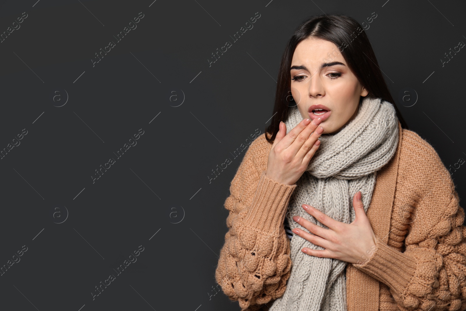Photo of Beautiful young woman coughing against dark background. Space for text