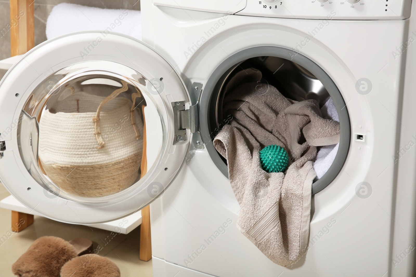 Photo of Green dryer ball and towels in washing machine drum indoors