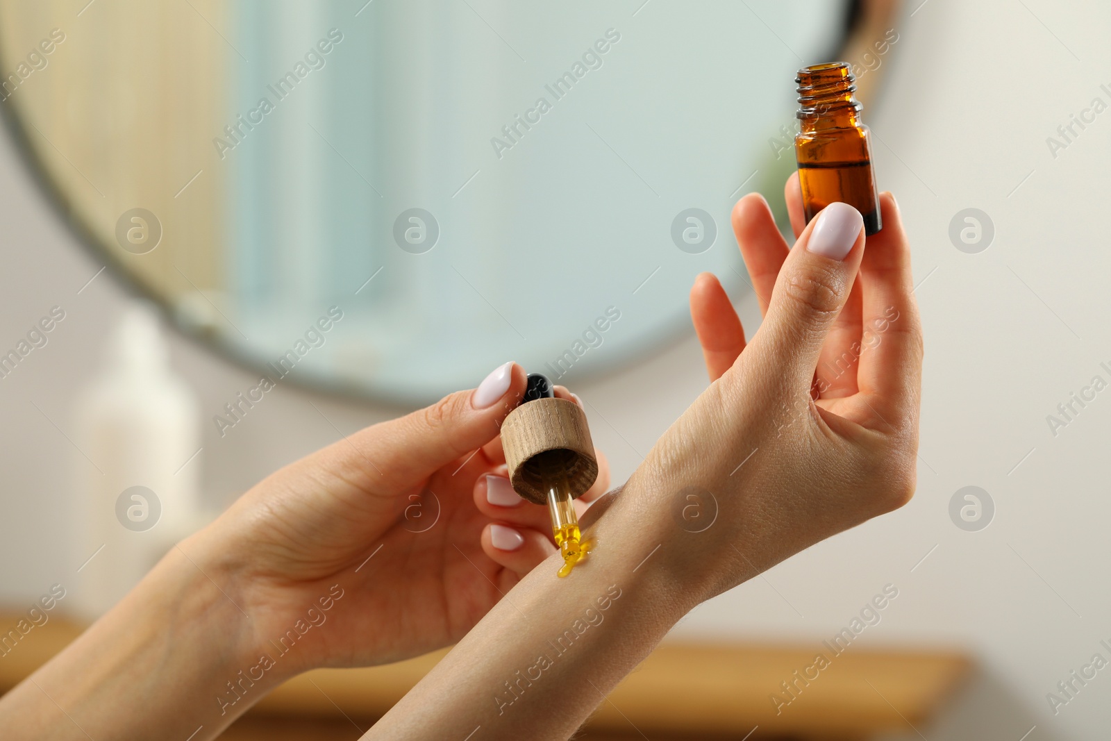 Photo of Young woman applying essential oil on wrist indoors, closeup