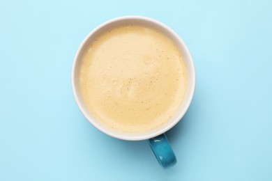 Fresh coffee in cup on light blue background, top view