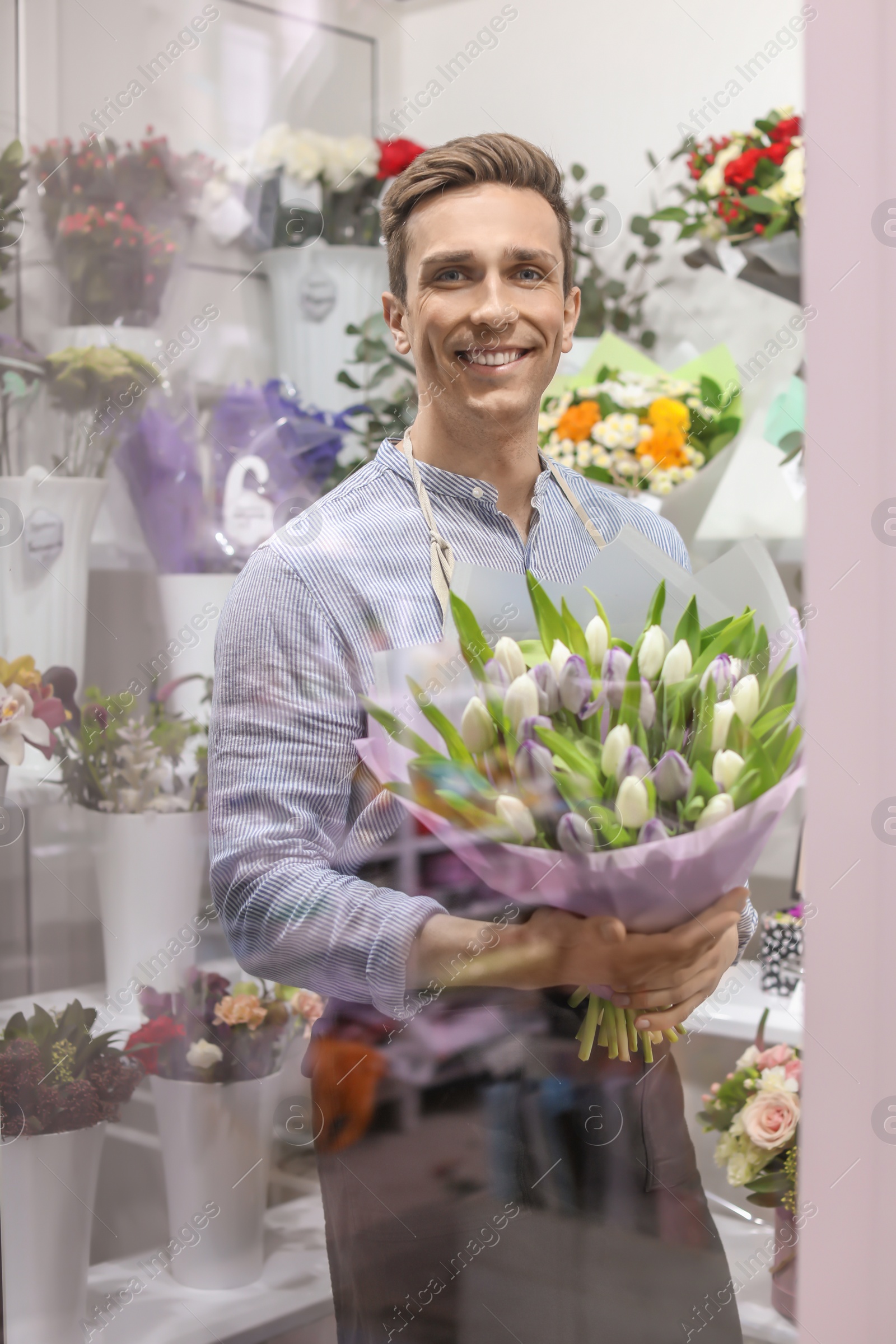 Photo of Male florist holding bouquet flowers at workplace