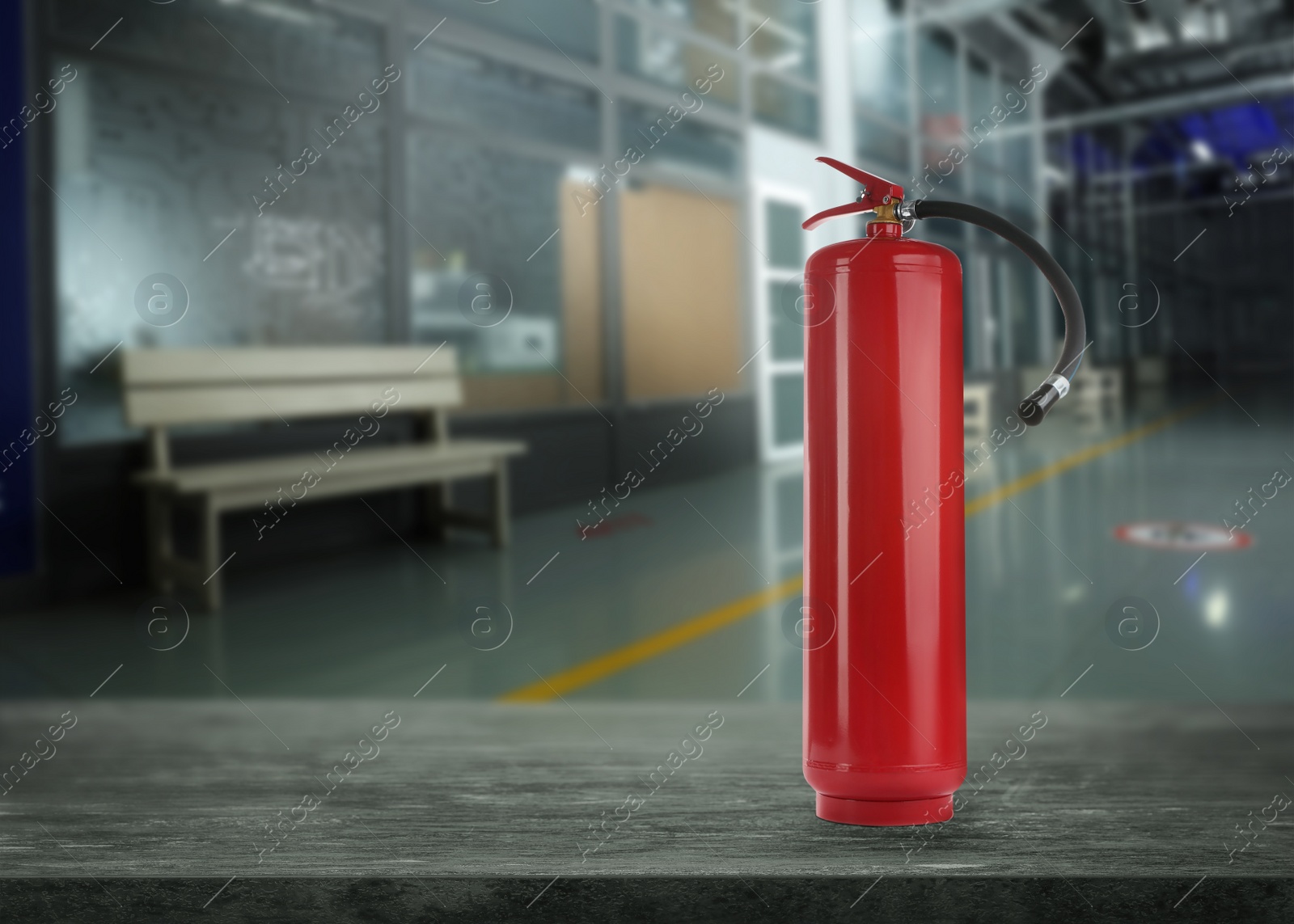 Image of Fire extinguisher on stone table in office corridor. Space for text