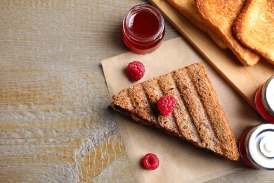 Tasty sandwich with raspberry jam for breakfast on wooden table, flat lay