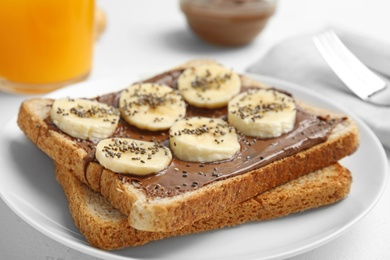 Photo of Slice of bread with chocolate paste and banana on table, closeup